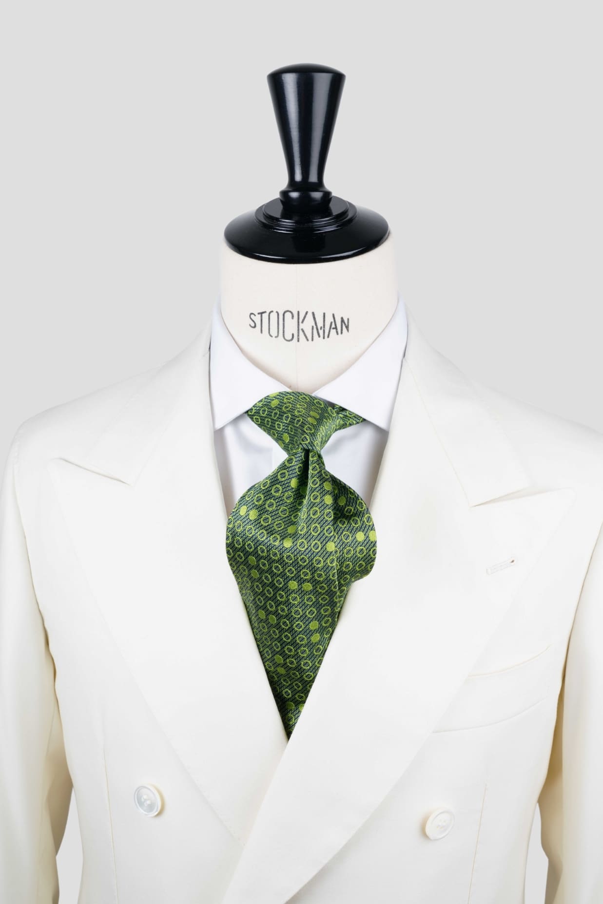 Cravate sartoriale à 7 plis, en soie tissée Jacquard verte, motif rond et aperçu du noeud simple sur buste Stockman.